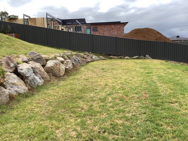 Finished lawn with rock edging below a residential boundary