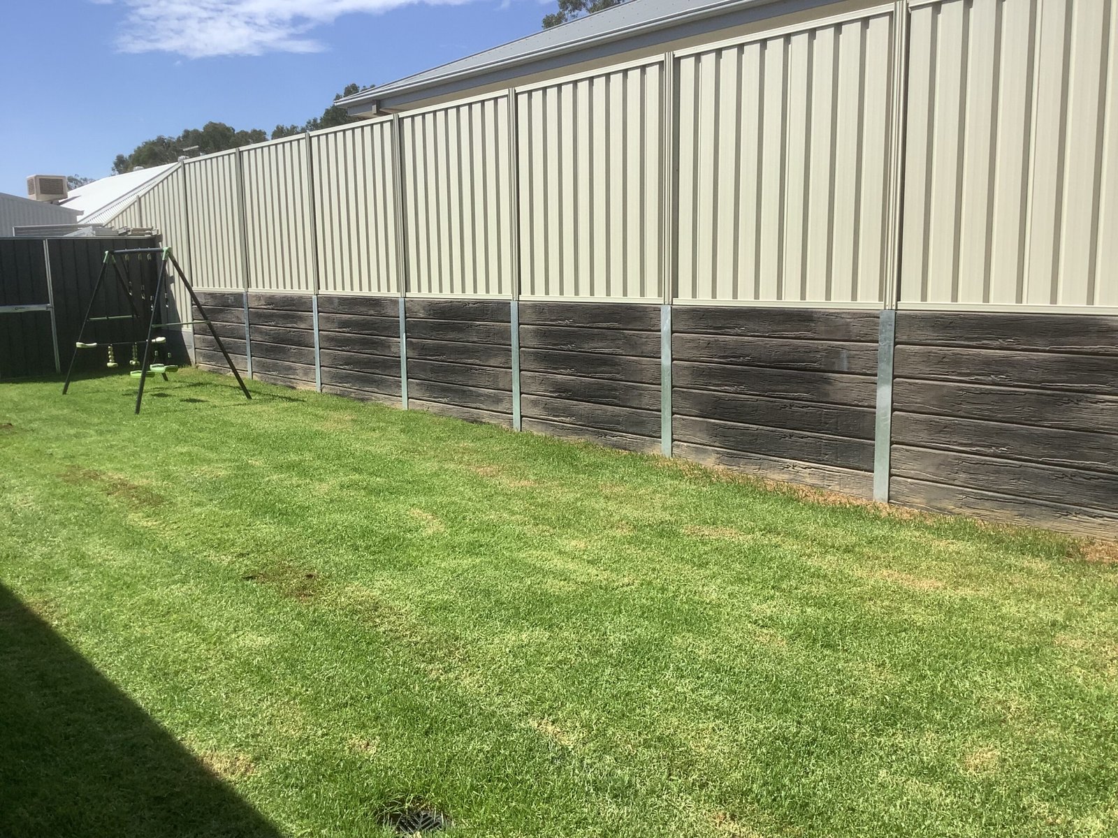Finished timber-look concrete sleeper retaining wall with lawn