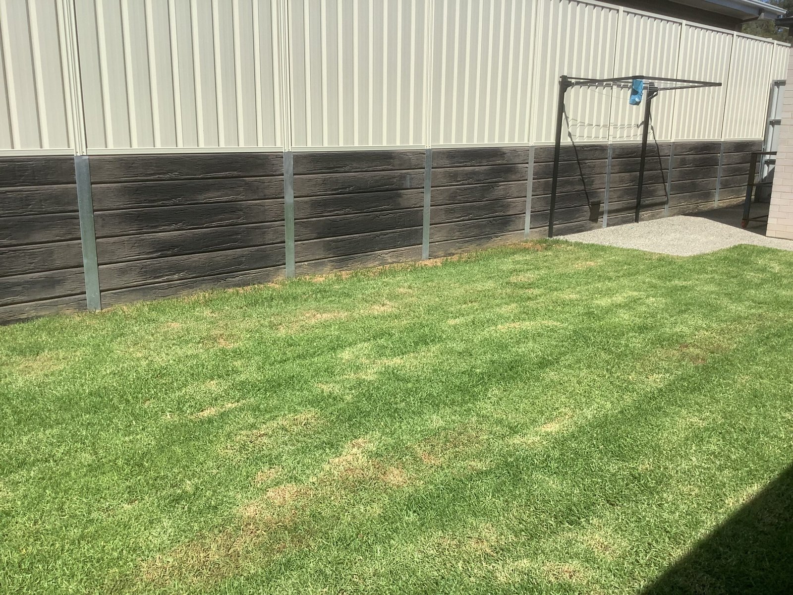 Finished lawn and timber-look retaining wall at a residential property