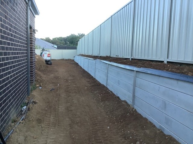 Finished concrete sleeper retaining wall beside a residential building