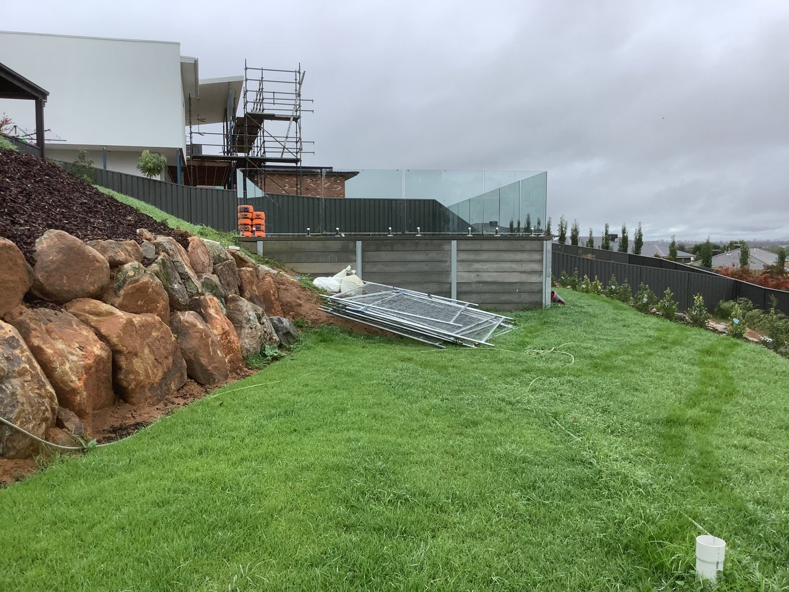Completed retaining wall with green lawn and rock landscaping