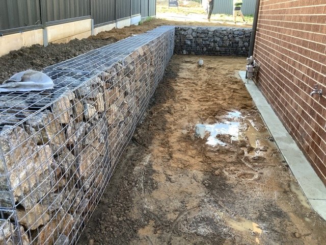 Gabion retaining wall construction beside a residential property