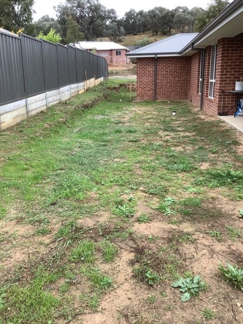Residential ground beside a home before retaining and landscaping work