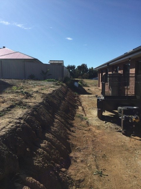 Excavated trench beside a residential property during earthworks