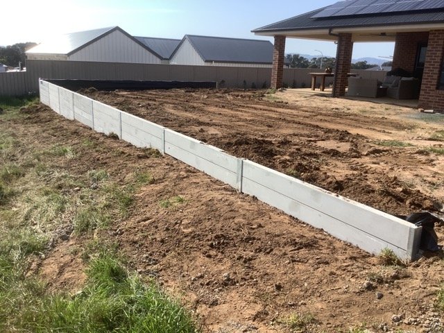 Long concrete sleeper retaining wall beside a residential building