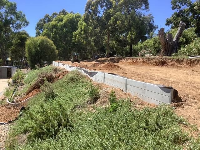 Completed concrete sleeper retaining wall along a shaped residential site